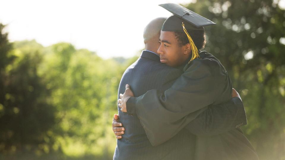 African American Father hugging his son graduation day.