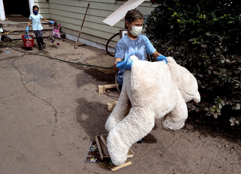 Young volunteers remove damaged toys from the Hossain-Miu home in Millburn, N.J., Saturday, Sept. 4, 2021, after flash floods from the remnants of Hurricane Ida inundated the neighborhood. Flood-stricken families and business owners across the Northeast are hauling waterlogged belongings to the curb and scraping away noxious mud as cleanup from Ida moves into high gear. (AP Photo/Craig Ruttle)