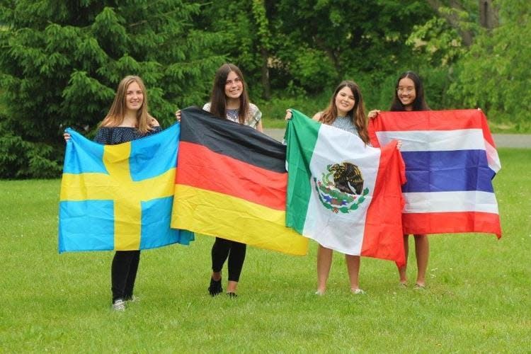 International students show off flags representing their home countries. ISE pairs host families with high school students from over 40 countries.