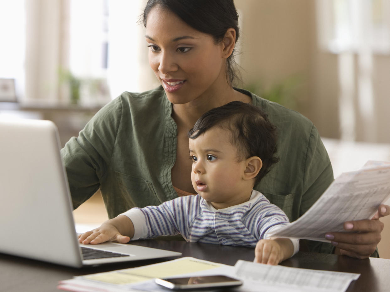 Mixed race mother working on computer with baby boy on her lap