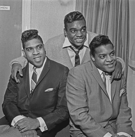 A black-and-white photo of three men smiling in suits