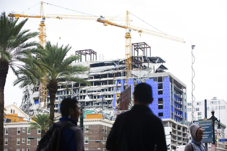 Pedestrians walk on Canal street near the Hard Rock Hotel construction site in New Orleans, Friday, Oct. 18, 2019. The Hard Rock Hotel partially collapsed last week leaving many workers injured, 3 confirmed dead. (Sophia Germer/The Advocate via AP)/