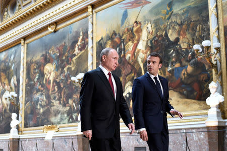 French President Emmanuel Macron (R) speaks to Russian President Vladimir Putin (L) in the Galerie des Batailles (Gallery of Battles) as they arrive for a joint press conference at the Chateau de Versailles before the opening of an exhibition marking 300 years of diplomatic ties between the two countries in Versailles, France, May 29, 2017. REUTERS/Stephane De Sakutin/Pool