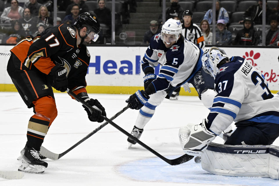 Anaheim Ducks left wing Alex Killorn, left, scores against Winnipeg Jets goaltender Connor Hellebuyck, right, and defenseman Brenden Dillon during the second period of an NHL hockey game in Anaheim, Calif., Sunday, Dec. 10, 2023. (AP Photo/Alex Gallardo)