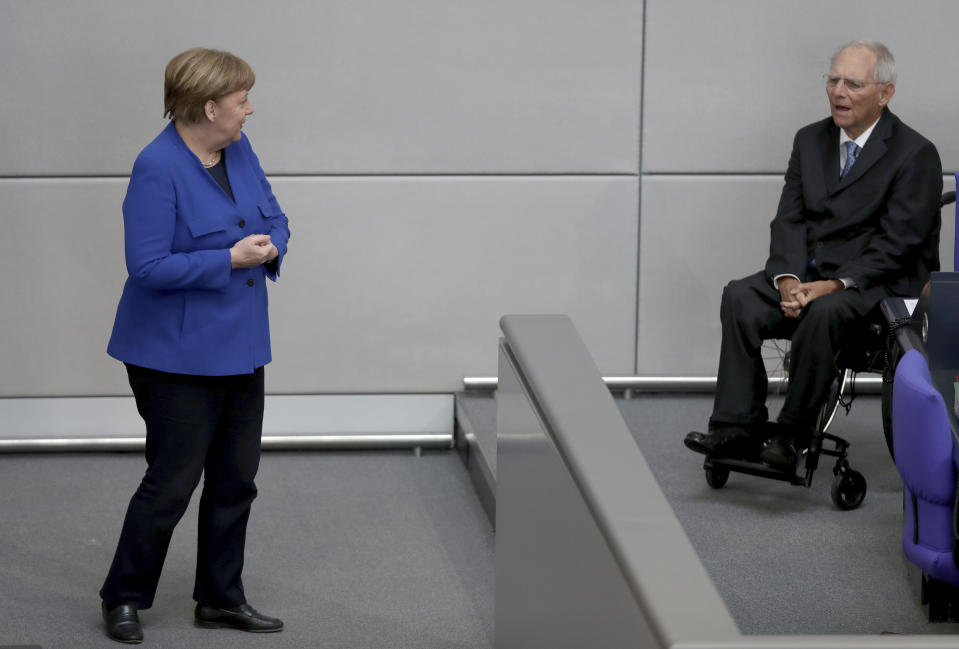 German Chancellor Angela Merkel, left, talks to the President of the Federal Parliament, Wolfgang Schaeuble, right, as she arrives for a meeting of the German federal parliament, Bundestag, at the Reichstag building in Berlin, Germany, Wednesday, May 13, 2020. (AP Photo/Michael Sohn)