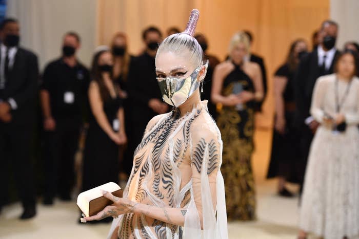 closeup of grimes at an event with a shiny metal mask covering the lower half of her face