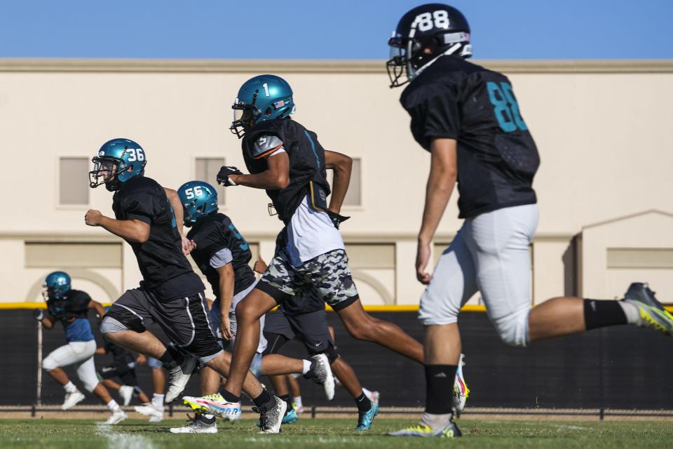 St. John Paul II wide receiver Jacob Carrillo (1), center, does warm-up runs during a team practice on Thursday, September 15, 2022, in Avondale. Carrillo was diagnosed with cancer and continues to receive chemotherapy as he plays on the football team.