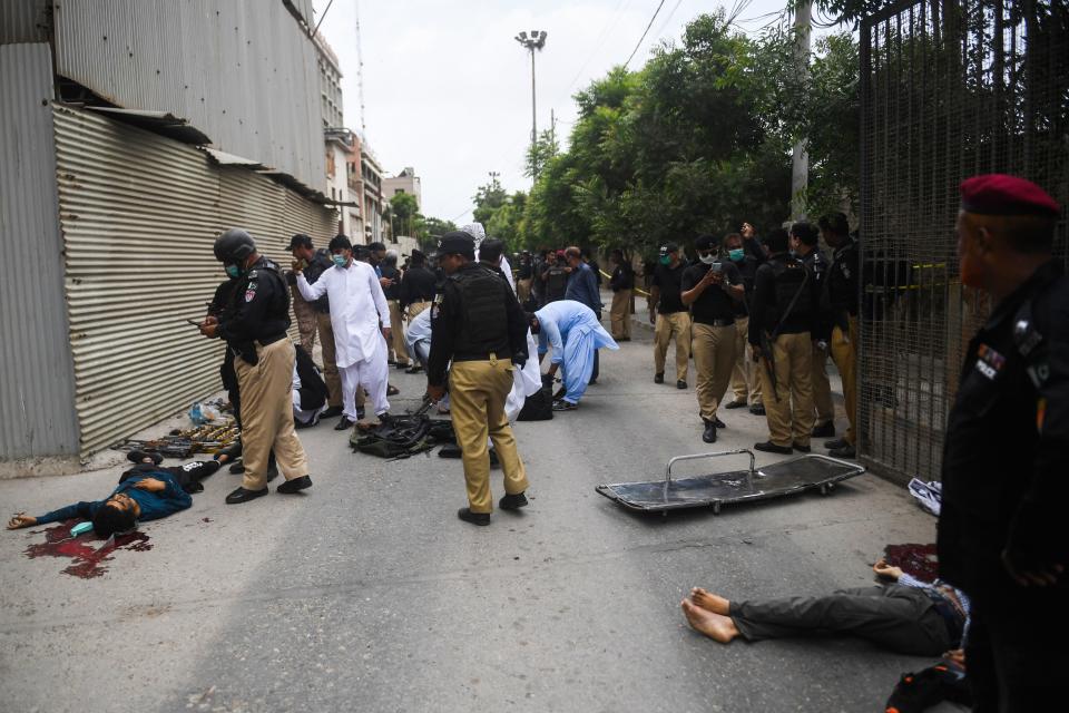 EDITORS NOTE: Graphic content / Police collect evidence next to the bodies of alleged gunmen outside the Pakistan Stock Exchange building in Karachi on June 29, 2020. - A group of gunmen attacked the Pakistan Stock Exchange in Karachi June 29, police said, with four of the attackers killed. (Photo by Asif HASSAN / AFP) (Photo by ASIF HASSAN/AFP via Getty Images)