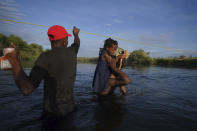A little girl holds on to her Barbie doll as she is carried over the Rio Grande river to Del Rio, Texas, as some migrants, many from Haiti, wade across in the opposite direction to return to Ciudad Acuna, Mexico, early Wednesday, Sept. 22, 2021, some to avoid possible deportation from the U.S. and others to load up with supplies. (AP Photo/Fernando Llano)