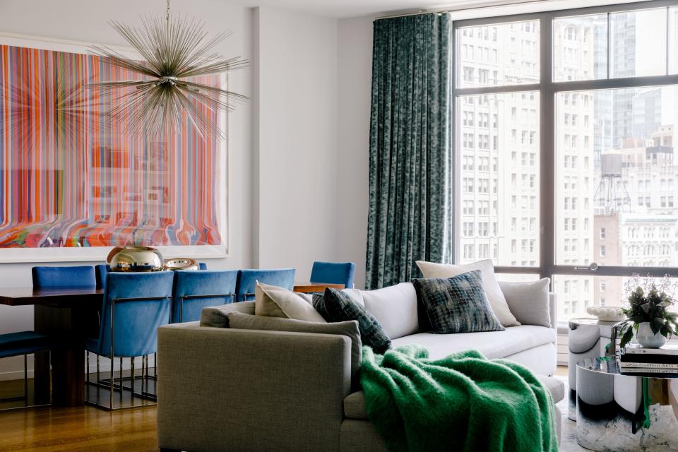 The family’s living and dining room area has stunning views onto Madison Square Park. The brightly hued painting near the dining room table is by Ian Davenport.