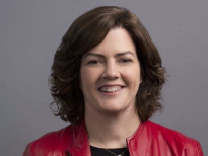 Marie Donoghue, Amazon's VP of global sports video, wears a black shirt and red jacket against a gray background.