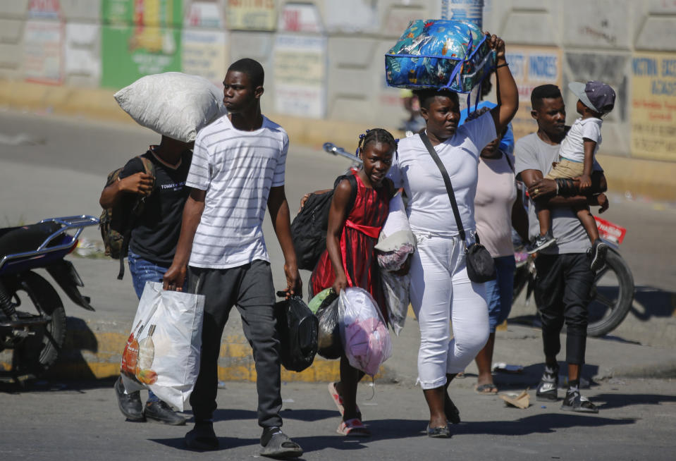 Residents of the Solino neighborhood, who were displaced from their homes due to clashes between armed gangs, seek shelter as they walk along a street in the Carrefour community of Port-au-Prince, Haiti, Thursday, Jan. 18, 2024. (AP Photo/Odelyn Joseph)