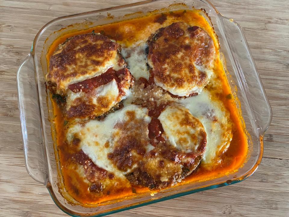 A fully cooked eggplant Parmesan in a glass pan.