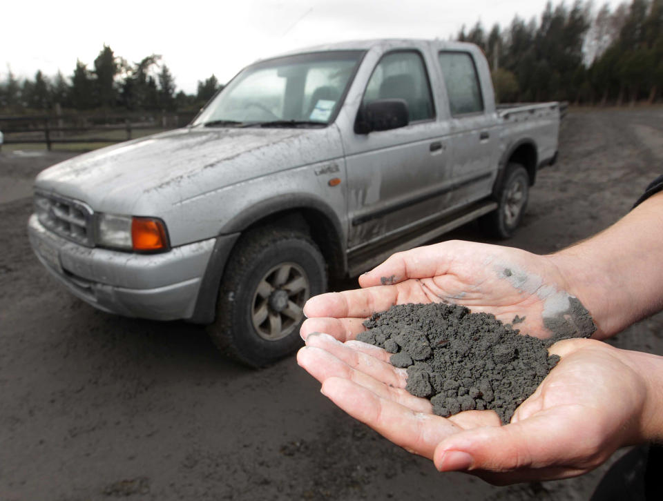 A man holds a handful of volcanic ashes that fell on a property in Rangipo near the base of Mt Tongariro, New Zealand after an eruption Tuesday, Aug. 7, 2012. The volcano in New Zealand's central North Island has erupted for the first time in more than a century, sending out an ash cloud that is causing road closures and the cancellation of some domestic flights. (AP Photo/New Zealand Herald, Alan Gibson) AUSTRALIA OUT, NEW ZEALAND OUT