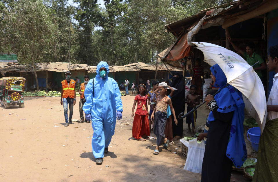 In this April 15, 2020, photograph, a health worker from an aid organization walks wearing a hazmat suit at the Kutupalong Rohingya refugee camp in Cox's Bazar, Bangladesh. There's been little if any coronavirus testing in Cox's Bazar, where more than a million members of Myanmar's Rohingya Muslim minority are packed into the world's largest refugee camp. (AP Photo/Shafiqur Rahman)