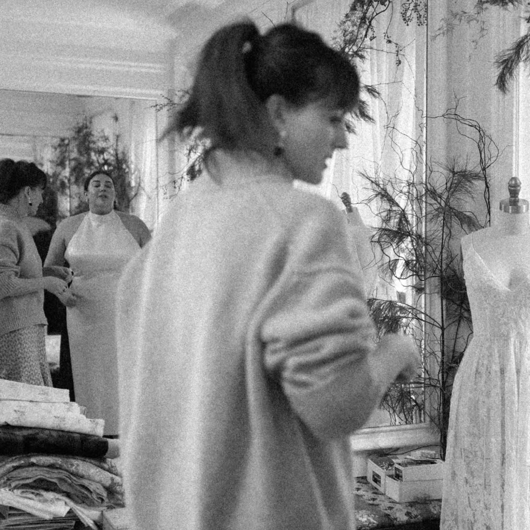  Bridal designer patricia voto stands in her studio with a bride while evaluating her outfit. 