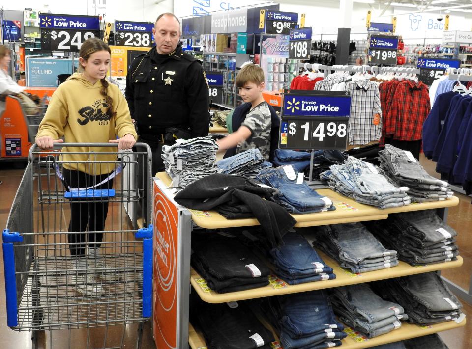 Sophia Walsh and her dad, Deputy Josh Walsh of the Coshocton County Sheriff's Office, shop with Micah Van Alstyne, 10, for the Coshocton Salvation Army Christmas Castle program at the Coshocton Walmart.