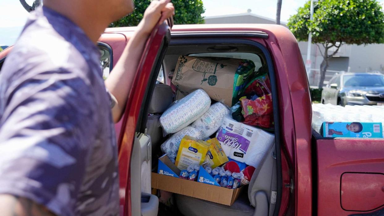 PHOTO: Dustin Akiona, 31, helps his cousin, Tyler Arbogast, 29, load up his truck with baby supplies and toiletries for residents in Lahaina, Hawaii, on Aug. 12, 2023. (Sandy Hooper/USA TODAY Network)