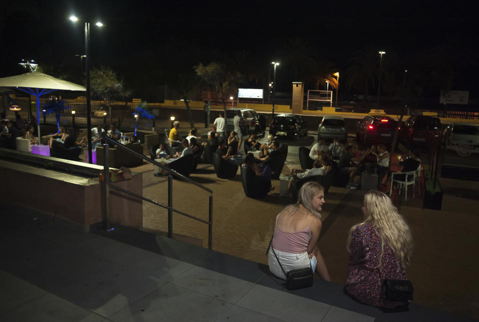 People sit outside a terrace bar in Fuengirola, near Malaga, Spain, Saturday, Aug. 8, 2020. The increase in Spain of coronavirus outbreaks associated with nightlife has set off alarms in recent days, mainly in tourist areas where pubs and discos are full before the summer tourist campaign. (AP Photo/Jesus Merida)