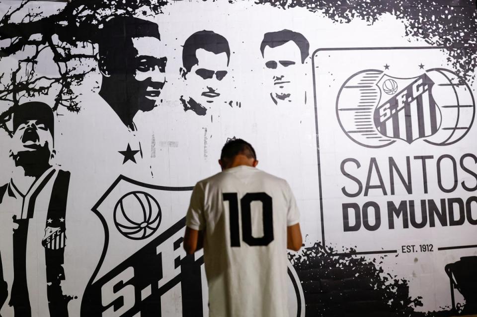A mourner stands in front of an image of Pele in Santos, Brazil (REUTERS)