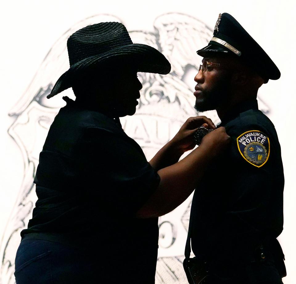 Felicia Owens, left, mother of new Milwaukee Police Officer Darell Owens, pins his badge on him during the police officer graduation at the Milwaukee Safety Academy in 2023. Owens was among 51 new officers who graduated.