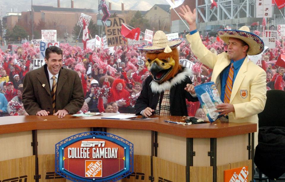 ESPN “GameDay hosts left to right: Chris Fowler, Lee Corso (in Swoop head) and Kirk Herbstreit ham it up with a bag of Tostitos.