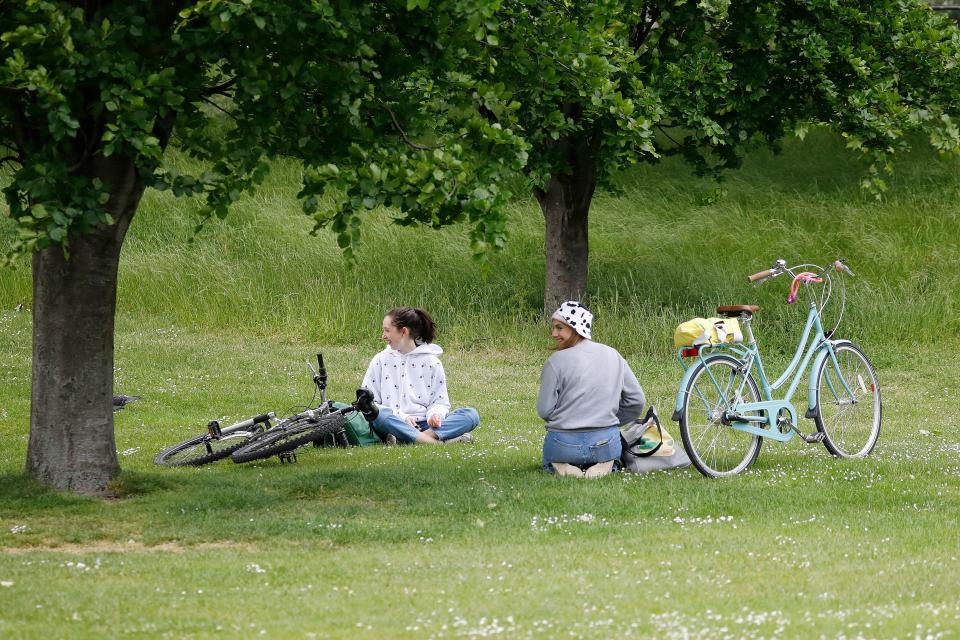 People sit near their bikes on the grass in St James's Park in London.