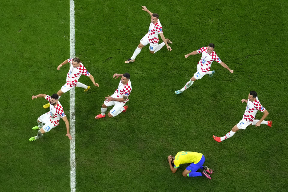 Brazil's Marquinhos is dejected after failing to score from the penalty spot as Croatia's players celebrate winning the World Cup quarterfinal soccer match between Croatia and Brazil, at the Education City Stadium in Al Rayyan, Qatar, Friday, Dec. 9, 2022. (AP Photo/Petr David Josek)