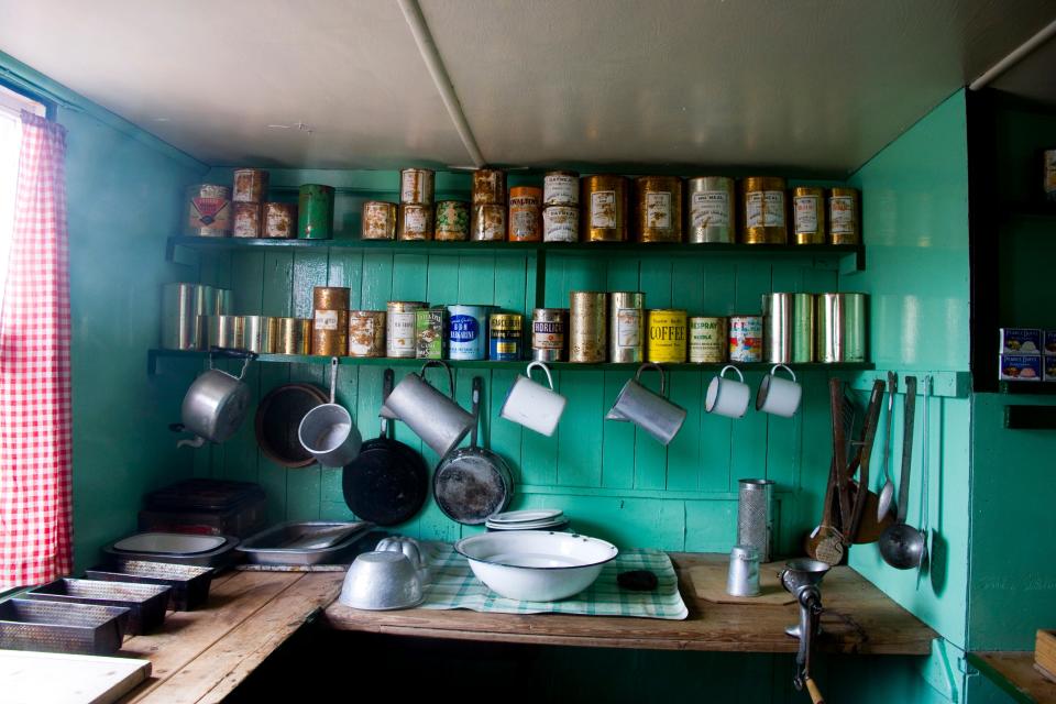an old-fashioned green kitchen with cans of shelves at the "Penguin Post Office," Port Lockroy on Goudier Island in Antarctica