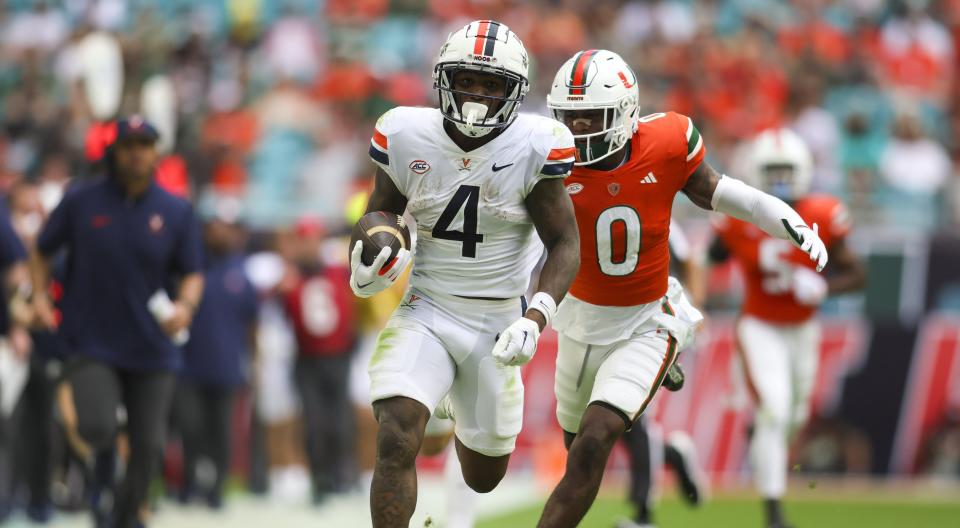 Oct 28, 2023; Miami Gardens, Florida, USA; Virginia Cavaliers wide receiver Malik Washington (4) runs with the football ahead of Miami Hurricanes cornerback Te'Cory Couch (0) during the second quarter at Hard Rock Stadium. Mandatory Credit: Sam Navarro-USA TODAY Sports