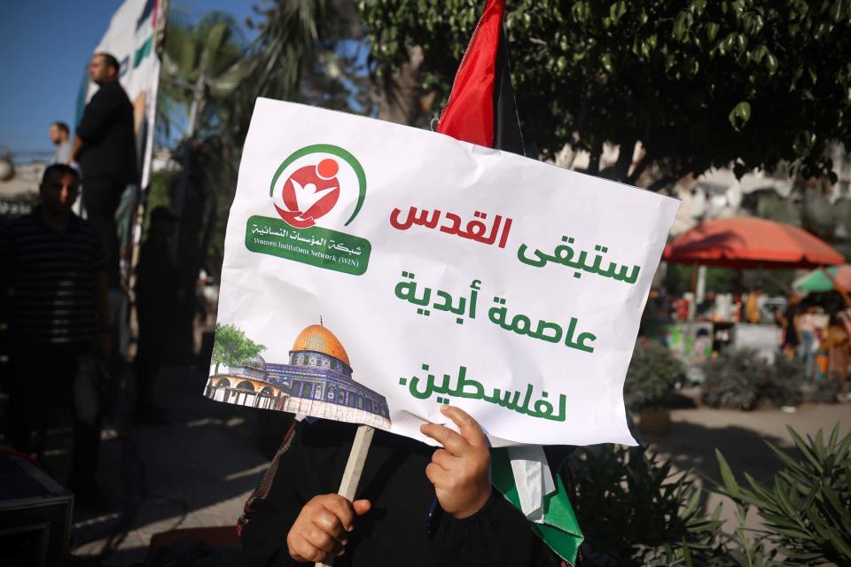 A Palestinian demonstrator carries a placard which reads ‘Jerusalem is the eternal capital of Palestine' during a gathering to protest the visit of US president Joe Biden, in Gaza City on 14 July 2022 (AFP via Getty Images)