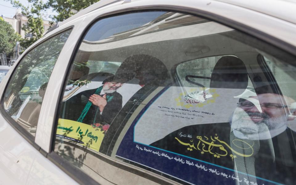 Posters of Ebrahim Raisi are reflected in a car window - Sam Tarling/Sam Tarling for The Telegraph