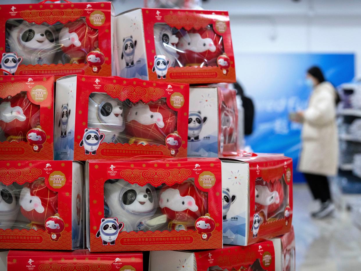 Visitors walk past merchandise for sale in a souvenir shop at a commercial plaza at the Winter Olympic Village in Beijing, Friday, Dec. 24, 2021. Organizers on Friday gave the media a look at parts of the athletes' Olympic Village for the 2022 Winter Olympics and Paralympics, which will be held beginning in February.