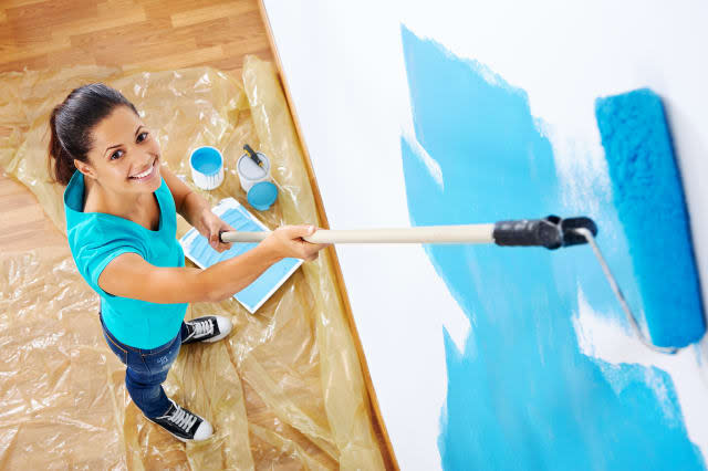 overhead view of woman painting new apartment standing on wooden floor