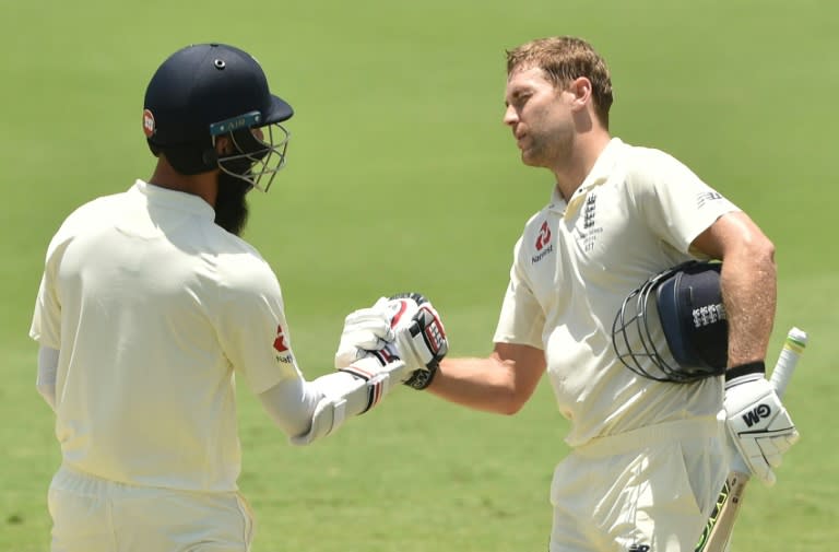 England's batsman Dawid Malan (R) celebrates his century with partner Moeen Ali on the third day of their four-day Ashes tour match against Cricket Australia XI, at the Tony Ireland Stadium in Townsville, on November 17, 2017