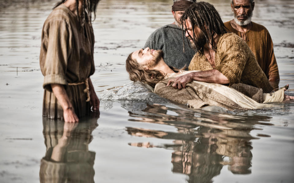 This publicity image released by History shows Diogo Morcaldo as Jesus, center, being baptized by Daniel Percival, as John, in a scene from "The Bible," premiering Sunday, March 3 at 8 p.m. EST on History. (AP Photo/History, Joe Alblas)