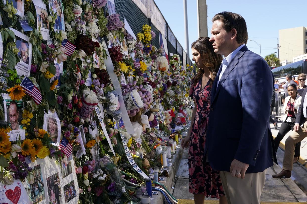 Florida Gov. Ron DeSantis, right, and his wife Casey tour a makeshift memorial near the Champlain Towers South condo building, where scores of victims remain missing more than a week after it partially collapsed, Saturday, July 3, 2021, in Surfside, Fla.