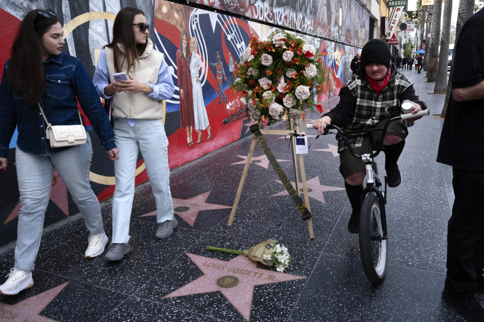 Pedestrians walk past a memorial wreath placed on the Hollywood Walk of Fame star for Louis Gossett Jr., in the Hollywood section of Los Angeles on Friday, March 29, 2024. Gossett was the first Black man to win a supporting actor Oscar and an Emmy winner for his role in the seminal TV miniseries "Roots," has died. He was 87. (AP Photo/Richard Vogel)