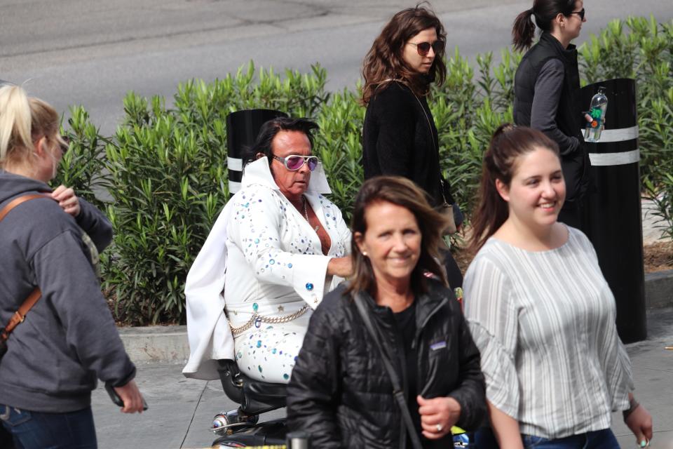 An Elvis impersonator rolls down the Strip on a motorized scooter.