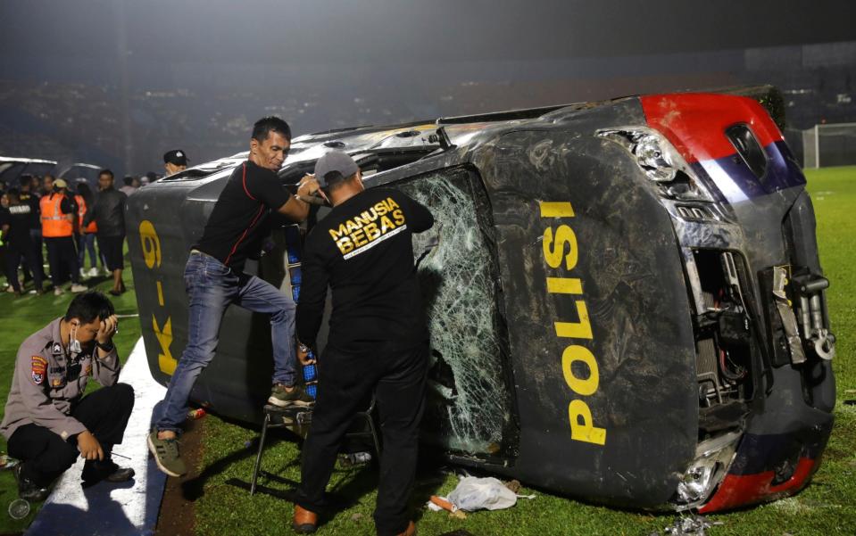 Police cars were overturned and torched on the pitch - AP Photo/Yudha Prabowo