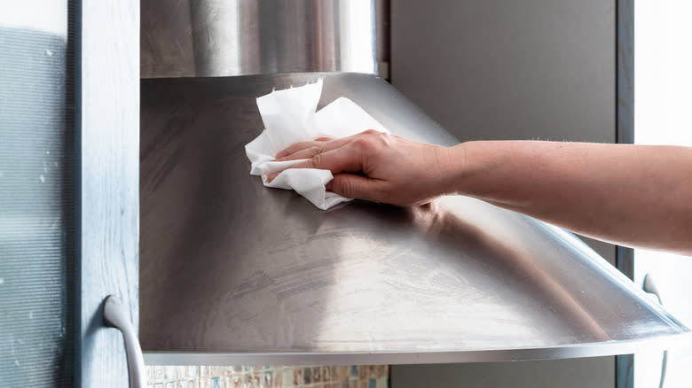 Person cleaning range hood exterior