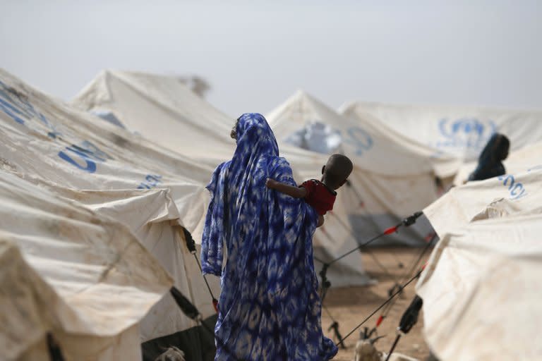 A women carries a child, on January 24, 2013 at a refugee camp in Menteao near the Malian border. French warplanes destroyed two Islamist bases in northern Mali as a leading Al Qaeda-linked group in the region split Thursday, with the breakaway group saying it wanted talks to end a Paris-led offensive against the militants