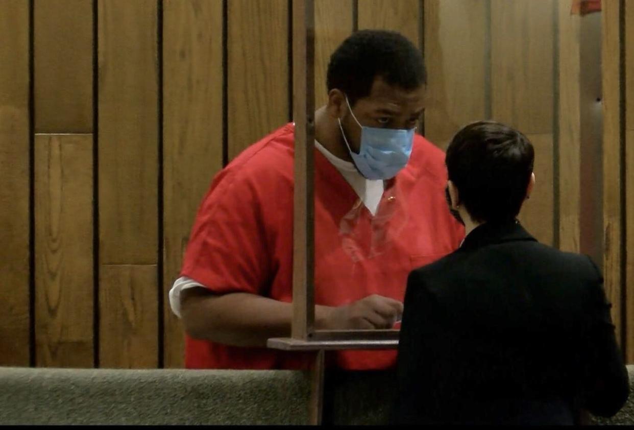 Patric Ferguson (in red) speaks through a clear barrier with defense attorney Lauren Fuchs after a court appearance on Jan. 14, 2021. He later leaned around the barrier to communicate better. Ferguson is accused of carrying out a kidnapping and killing while on duty as a Memphis Police Department officer. Fuchs said he's pleading not guilty.