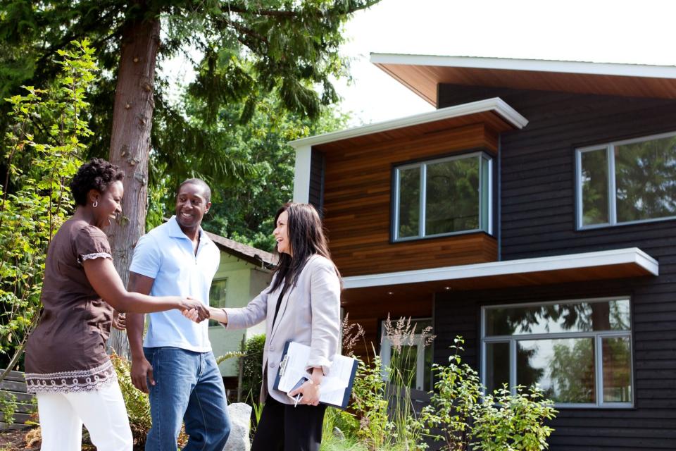 Real estate agent greeting couple at house