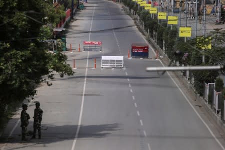 Indian security personal stand guard on a deserted road during restrictions on the Eid-al-Adha after the scrapping of the special constitutional status for Kashmir by the Indian government, in Srinagar