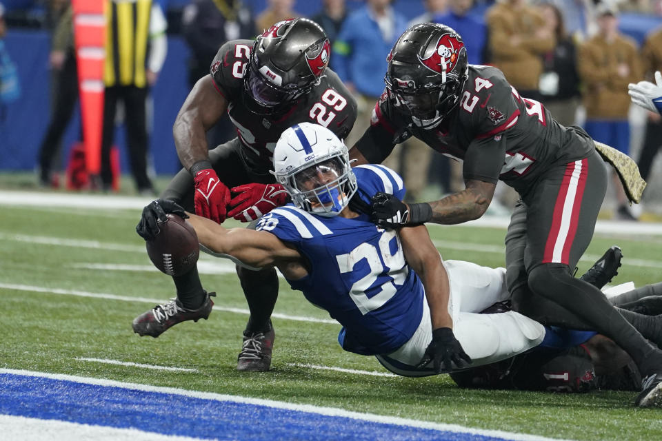 Indianapolis Colts running back Jonathan Taylor (28) reaches for a touchdown as Tampa Bay Buccaneers safety Christian Izien (29) and cornerback Carlton Davis III (24) try to stop him during the second half of an NFL football game Sunday, Nov. 26, 2023, in Indianapolis. (AP Photo/Michael Conroy)