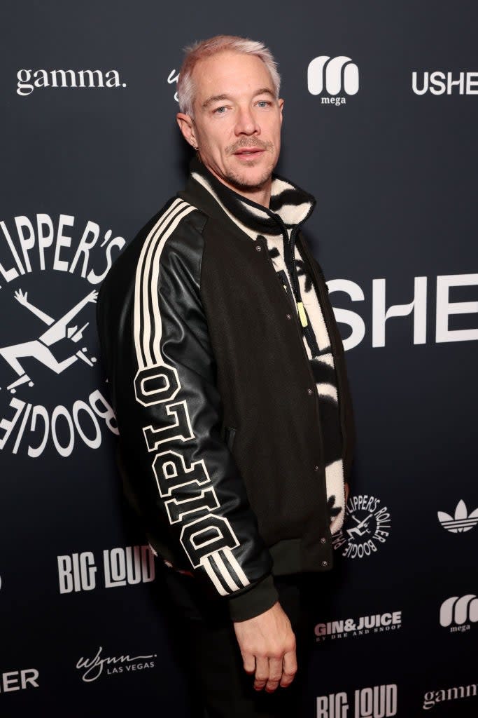 Diplo in a varsity jacket standing on the event backdrop