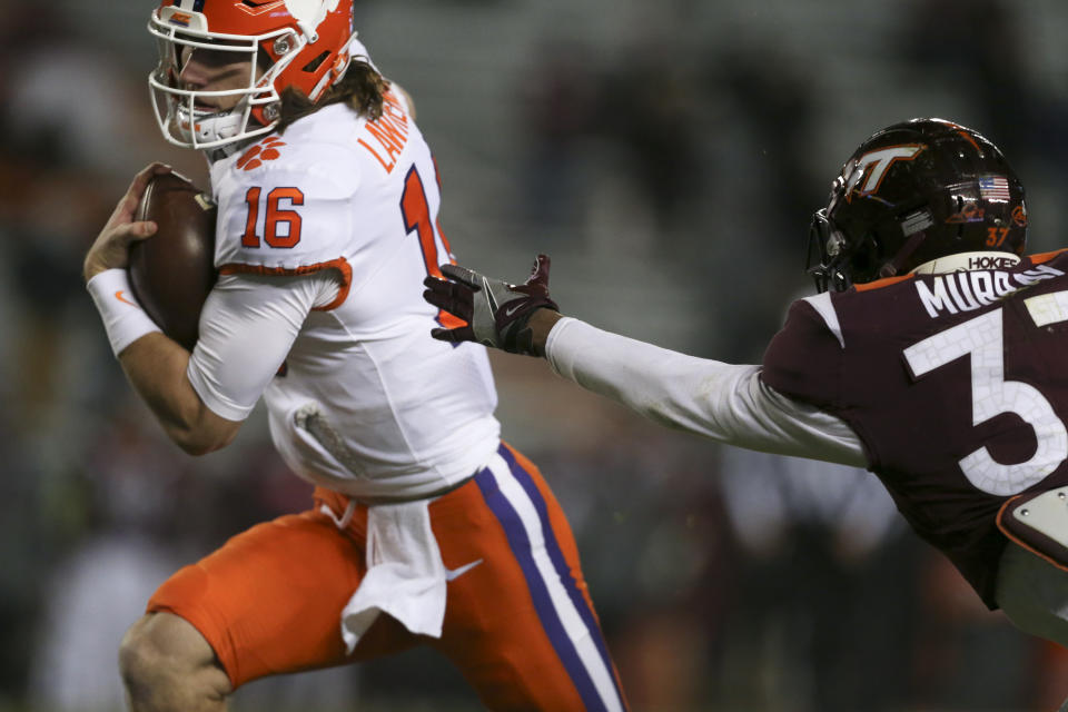 Clemson' Trevor Lawrence runs for a 17-yard touchdown past Virginia Tech's Brion Murray during the first quarter of an NCAA college football game Saturday, Dec. 5, 2020, in Blacksburg, Va. (Matt Gentry/The Roanoke Times via AP, Pool)