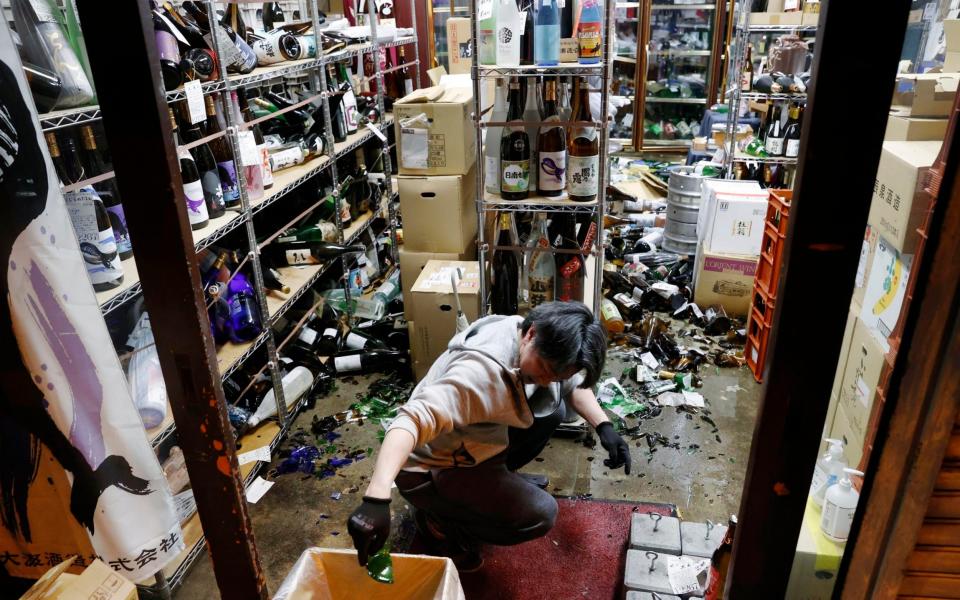 A liquor shop's manager clears the damaged bottles  - Kyodo News