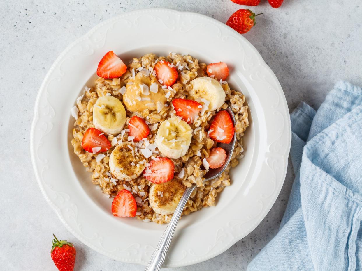 Oatmeal with banana, strawberries and peanut butter in a white plate.